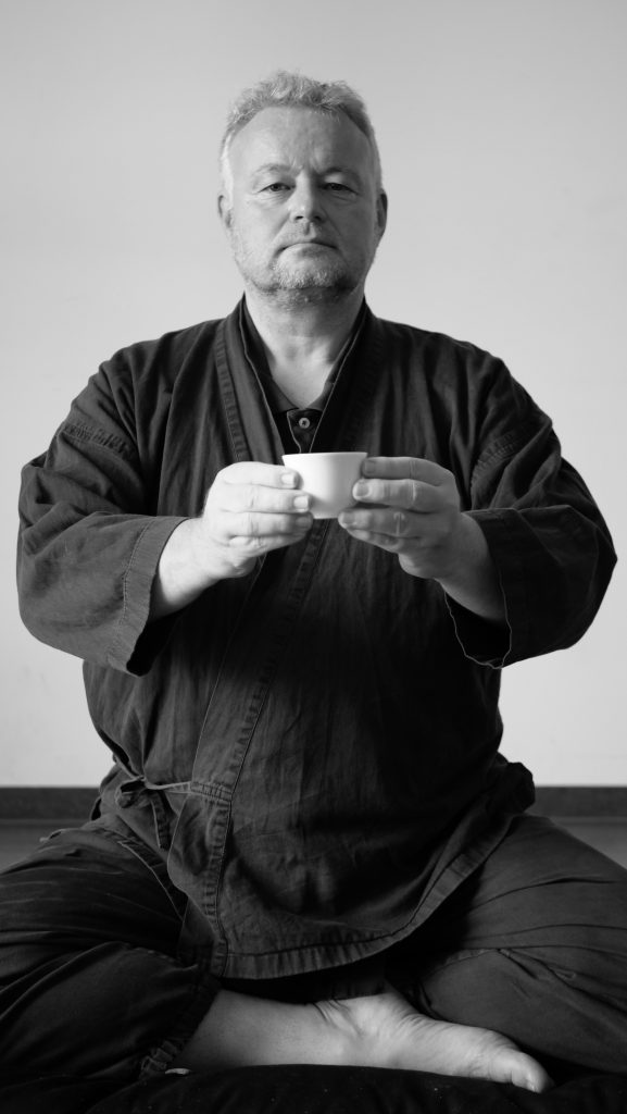 ZEN Südpfalz - Teezeremonie, Meditierender, der eine Tasse Tee vor sich hält