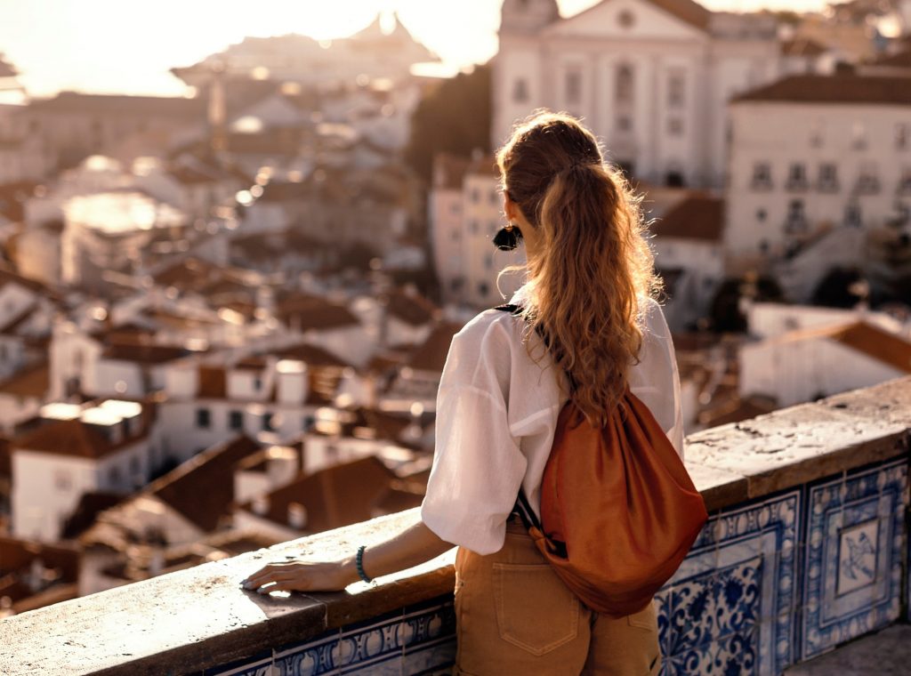 Eine Frau an einer Mauer mit der Aussicht über eine Stadt. Soll stehen für Einsicht und Veränderung.